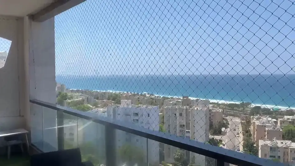 רשת נגד יונים שקופה במרפסת גבוהה עם נוף לים – הנוף נשמר